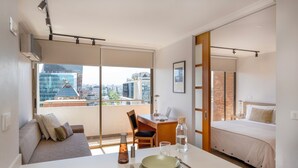 A modern hotel room with a balcony, a dining area, and a bed.