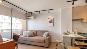 A modern apartment with a sofa, a dining area, and a kitchen.