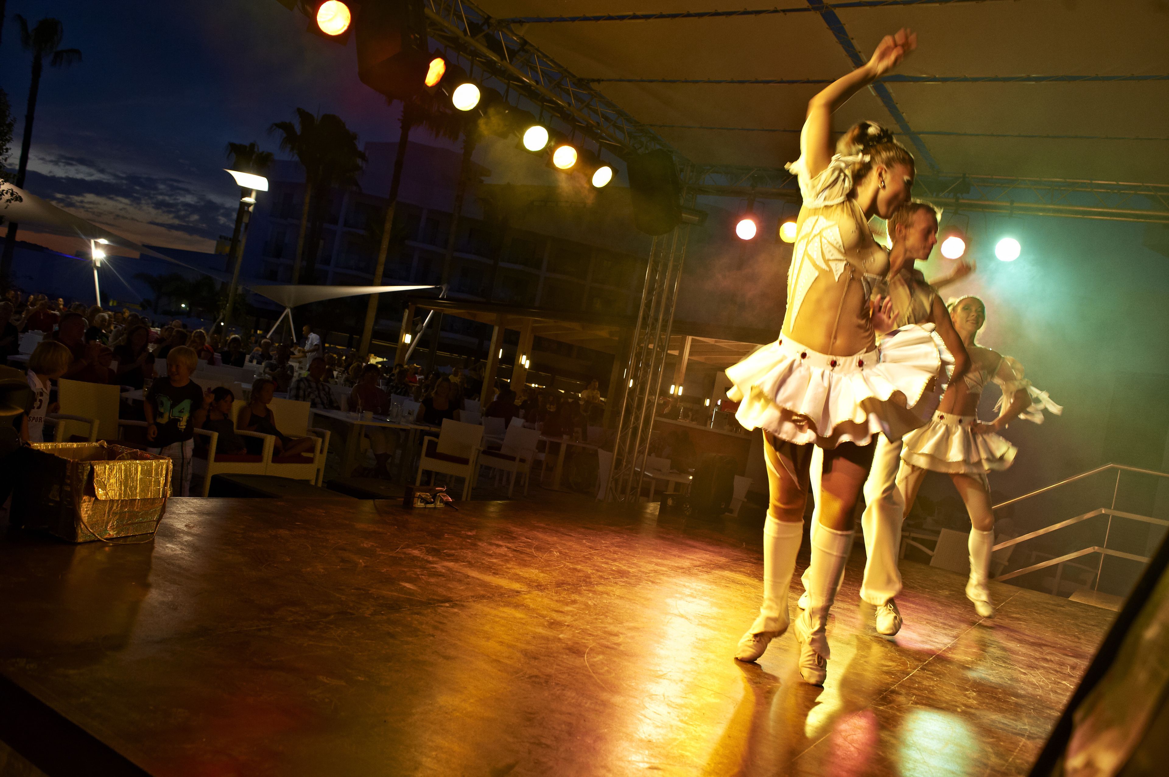 Un escenario con bailarines actuando bajo una carpa.