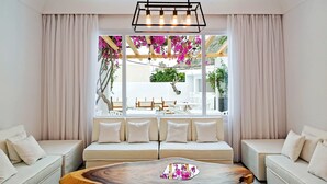 Un salon moderne doté d’une grande fenêtre, d’une table basse en bois et d’un ensemble de canapés beige.