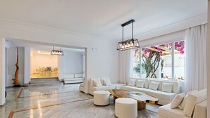 Un salon spacieux avec un grand canapé, une table basse et un coin repas à l’arrière-plan.