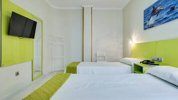 A hotel room with two beds, a TV mounted on the wall, a painting of a dolphin, and a green accent wall.
