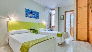 Habitación de hotel con dos camas, un cabecero verde, un cuadro de delfines y un armario de madera.