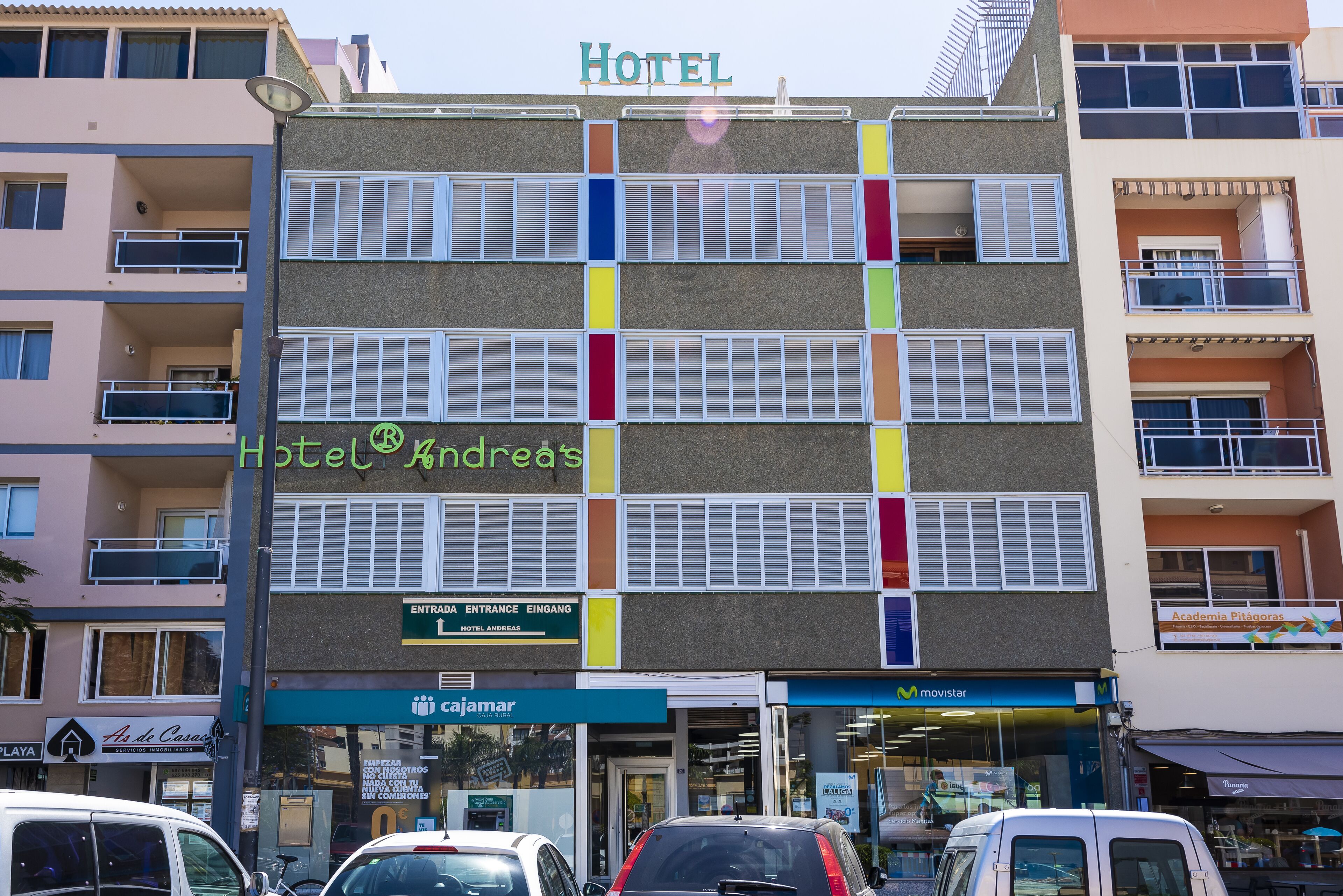 Un hôtel à plusieurs étages doté de balcons, une enseigne indiquant « Hôtel Andredes » et un magasin « Movistar » situé au rez-de-chaussée.