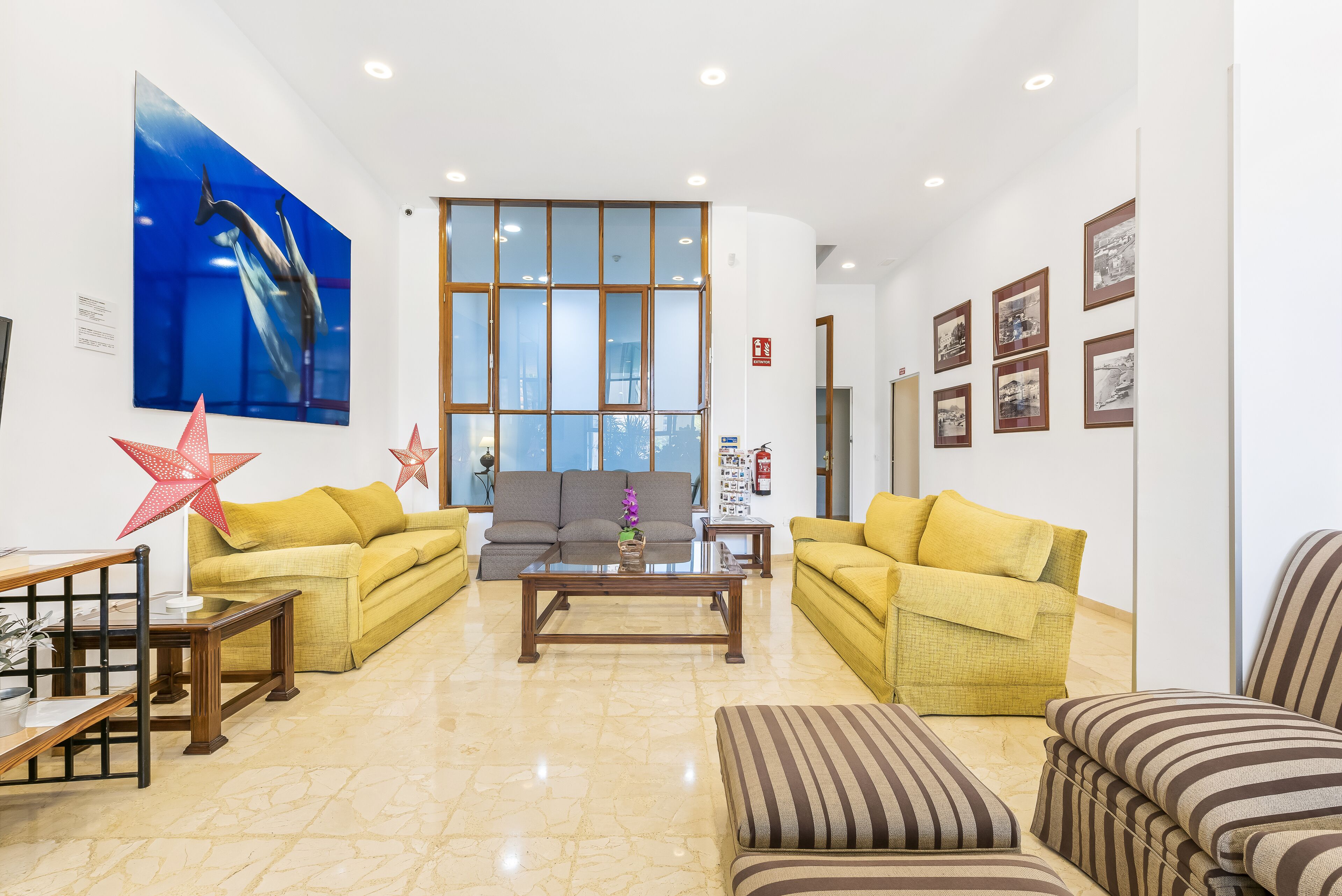 A spacious lobby with a large window, two sofas, a coffee table, and a striped ottoman.