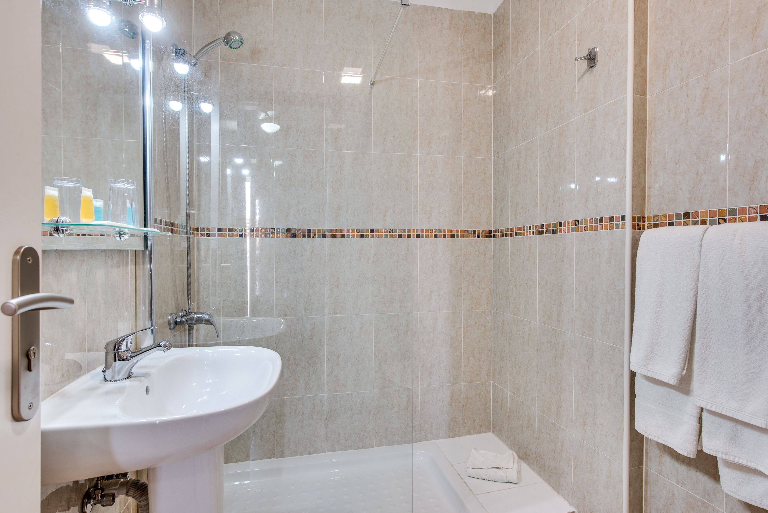 Un baño moderno con lavamanos, espejo y ducha.