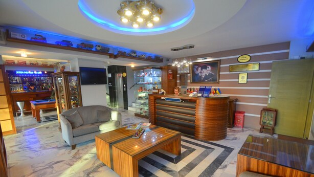 Een hotel lobby met een receptiebalie, een zithoek en een bar.