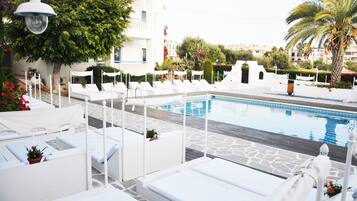 Un espace aménagé au bord de la piscine, avec des chaises longues blanches et une piscine.