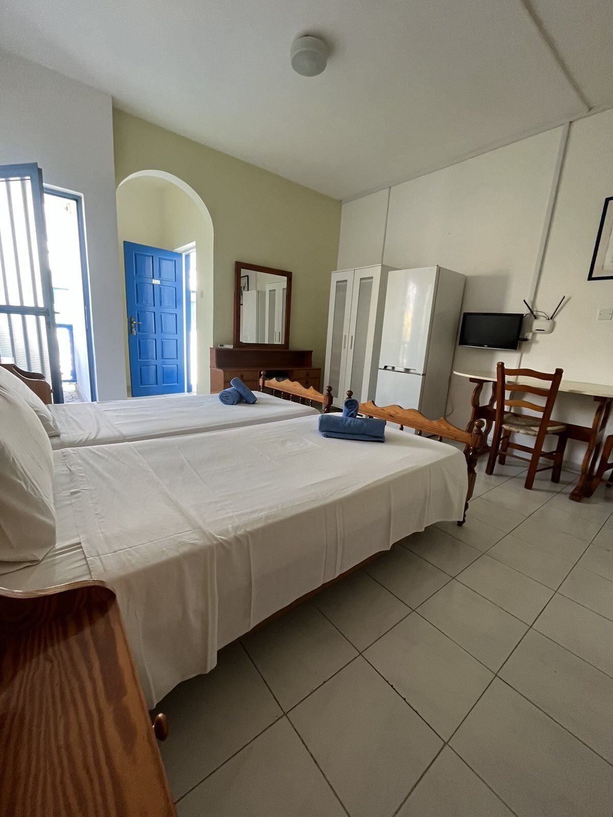 A hotel room with two beds, a desk with a chair, a television, and a wardrobe.