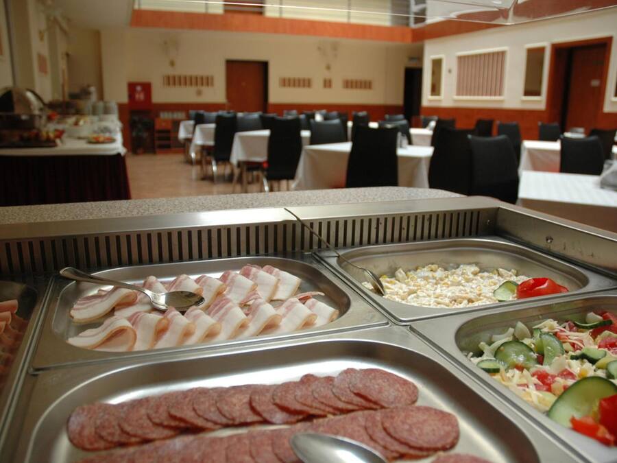 Zona de bufé con diversas opciones de comida, incluyendo tocino, maíz y una ensalada.