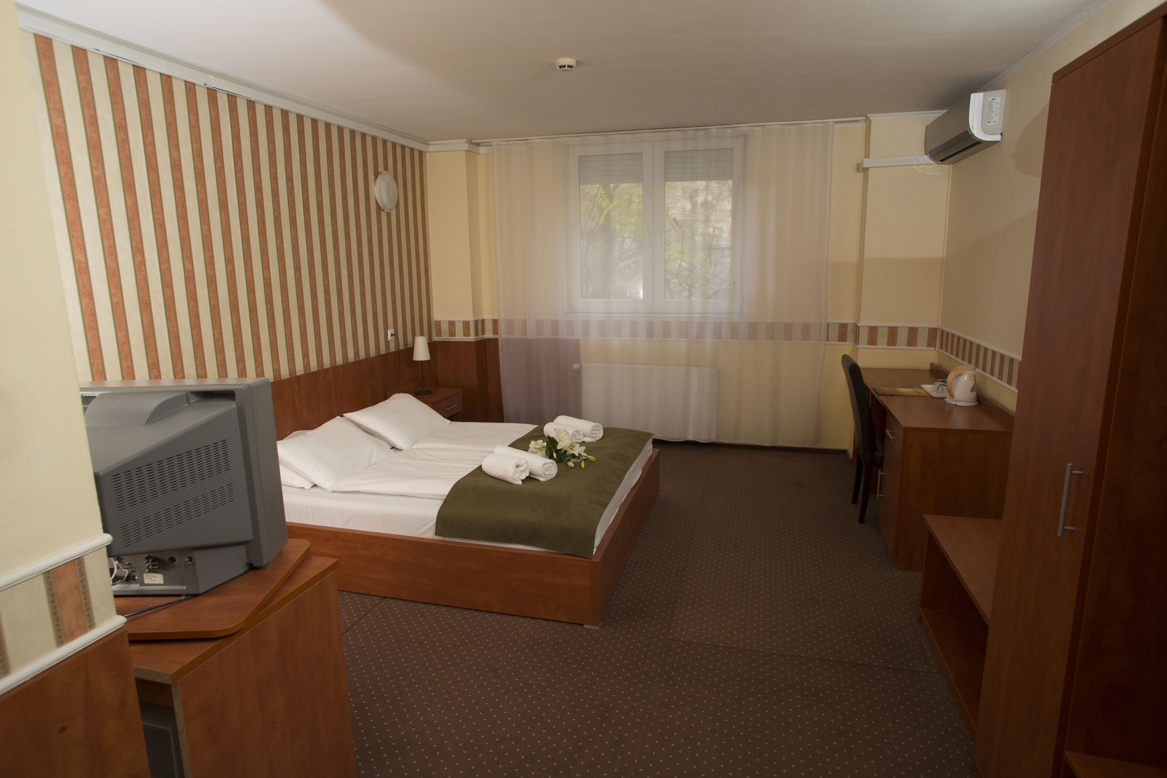 Una habitación de hotel con una cama, un escritorio, un televisor y un armario.