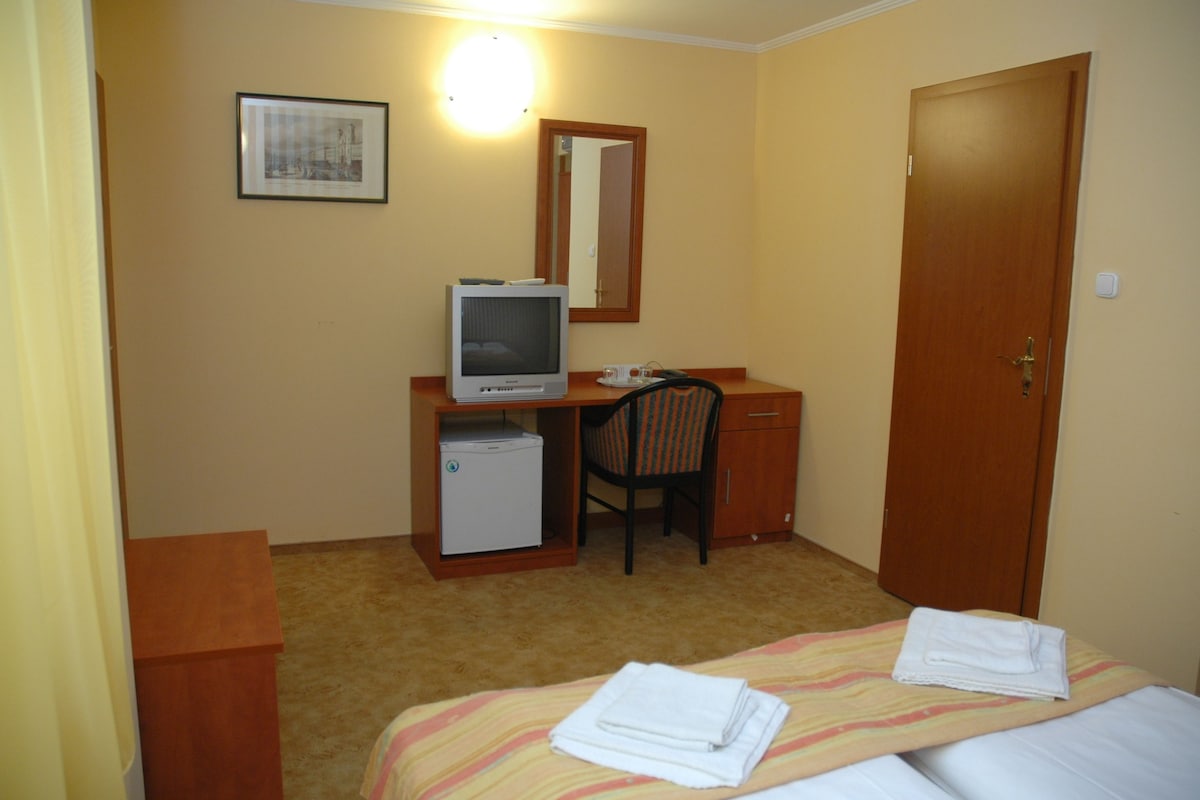 Una habitación de hotel con una cama, un escritorio con televisor, una silla y una puerta.