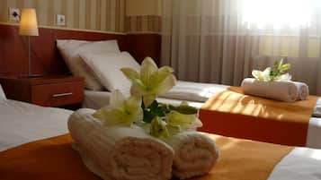 Una habitación de hotel con cama, mesita de noche, lámpara y ventana con cortinas.