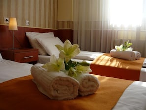 A hotel room with a bed, a nightstand, a lamp, and a window with curtains. - Atlantic (Budapest)