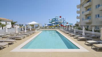 Een buitenzwembad, ligstoelen bij het zwembad