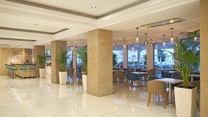 A modern hotel lobby with a bar area, seating arrangements, and large windows offering views. -  Sunrise Oasis Hotel & Waterpark (Paralimni)