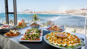 A table with various dishes and a view of the ocean and buildings.