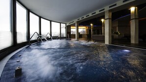 A large indoor hot tub with a view of the city skyline through large windows.