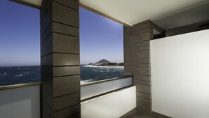 A balcony with a view of the ocean and a distant mountain.