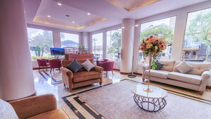 A spacious lobby with a sofa, chairs, a coffee table, and a TV. - Sonesta Hotel Loja (Loja)