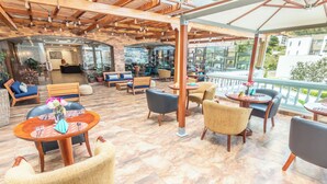A spacious outdoor seating area with wooden furniture and a view of the city. - Sonesta Hotel Loja (Loja)