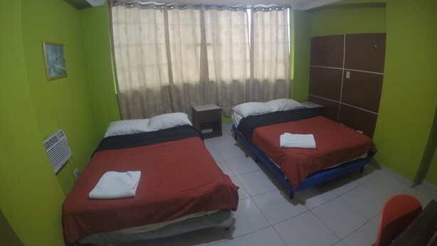 A room with two beds, a window with curtains, a radiator, and a wardrobe.