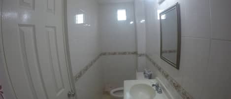 Un baño pequeño con inodoro, lavamanos y espejo.