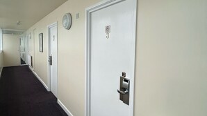 Pasillo de hotel con puertas blancas, cada una con un número y una cerradura.