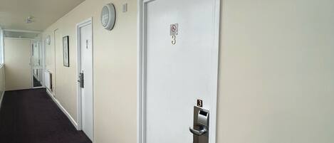 A hotel hallway with white doors, each marked with a number and a keyhole.