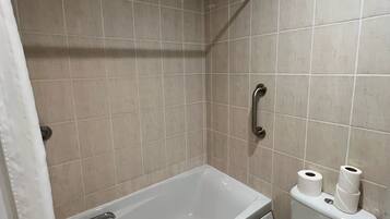 A bathroom with a bathtub, toilet, and shower area.