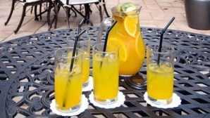 Un patio al aire libre con una mesa lista para comer, rodeada de sillas y un gran ventanal al fondo.