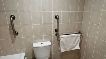 A small, modern bathroom with a toilet, grab bars, a towel rack, and a bathtub.