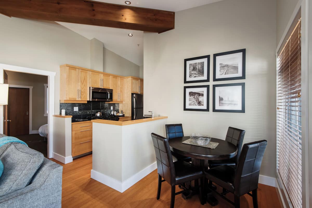 Una cocina moderna con armarios de madera, una isla central y un comedor con mesa y sillas.