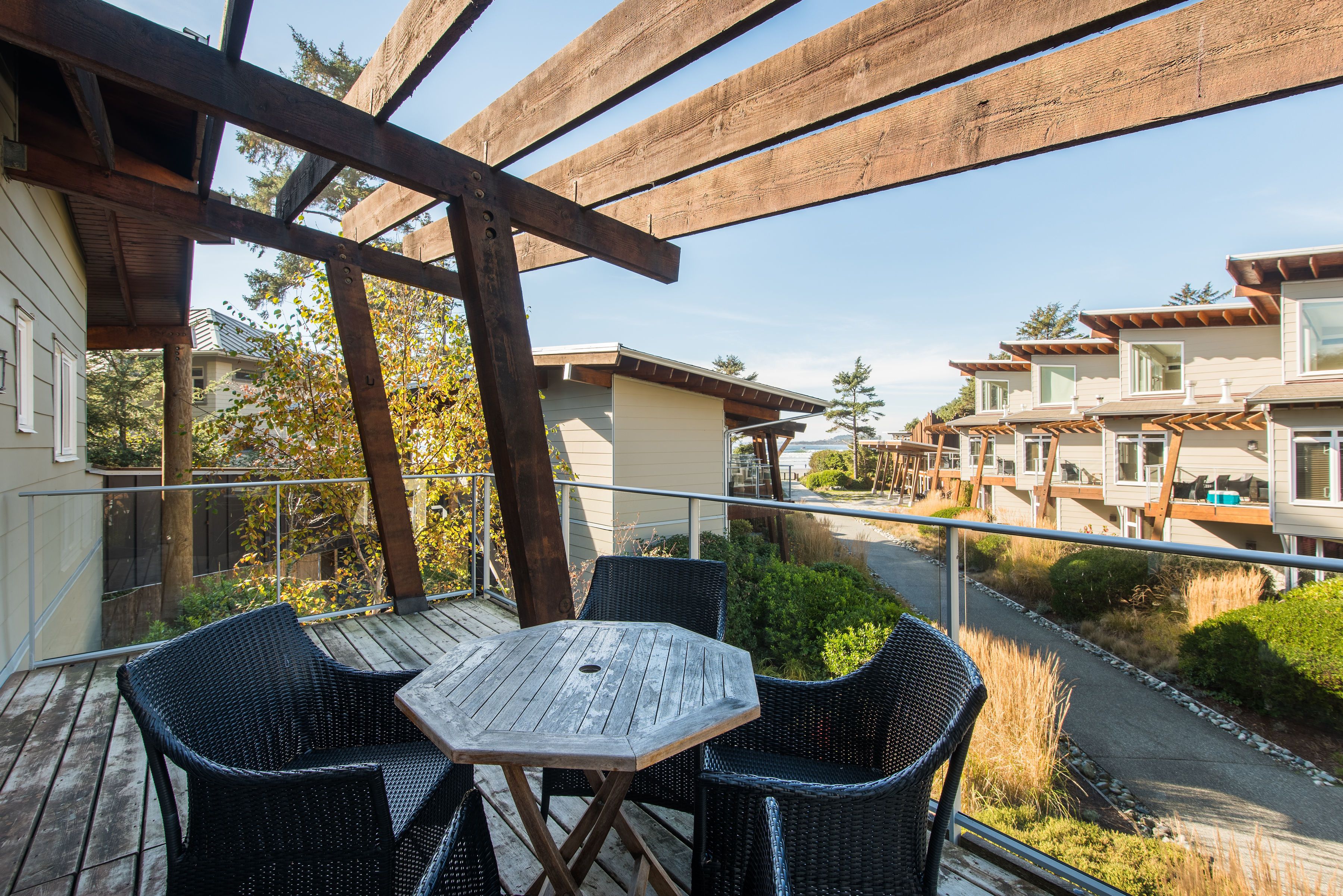 A wooden deck with a table and chairs, overlooking a residential area with houses and greenery.