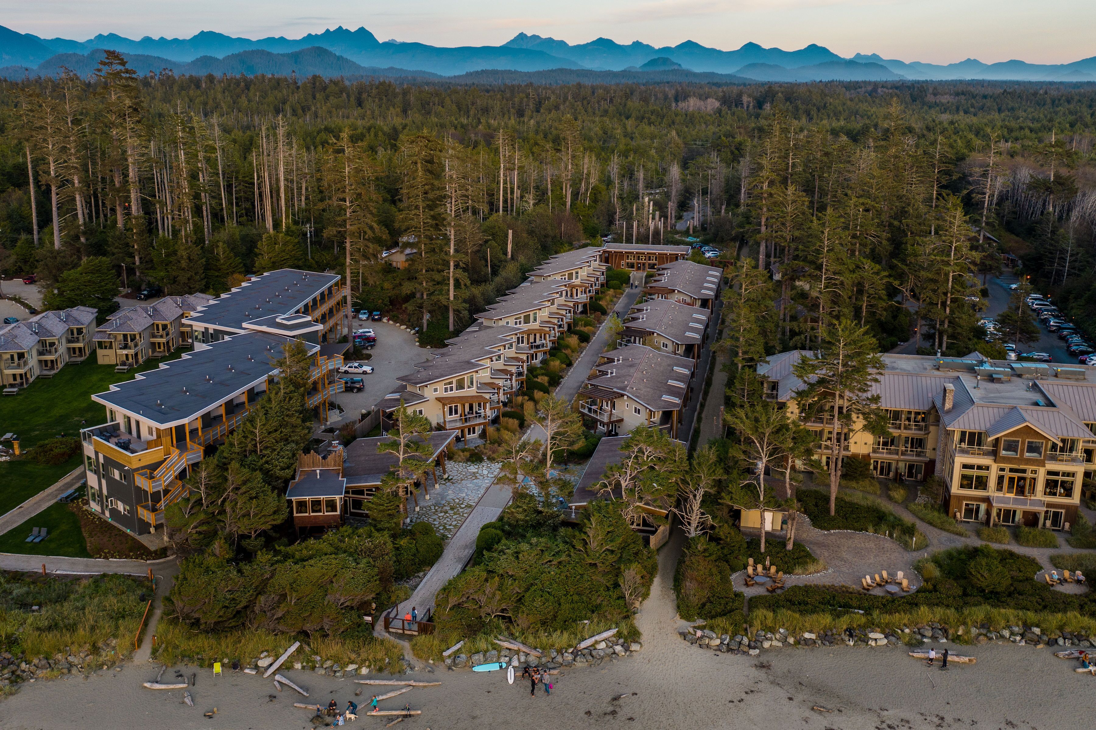 A resort with multiple buildings, a beach, and a forested area.