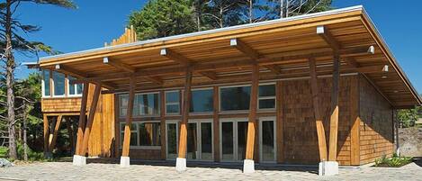 Ein modernes Holzhaus mit geneigtem Dach und großen Glasfenstern.