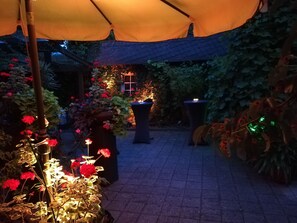 A garden area with a tiled floor, potted plants, and a canopy.