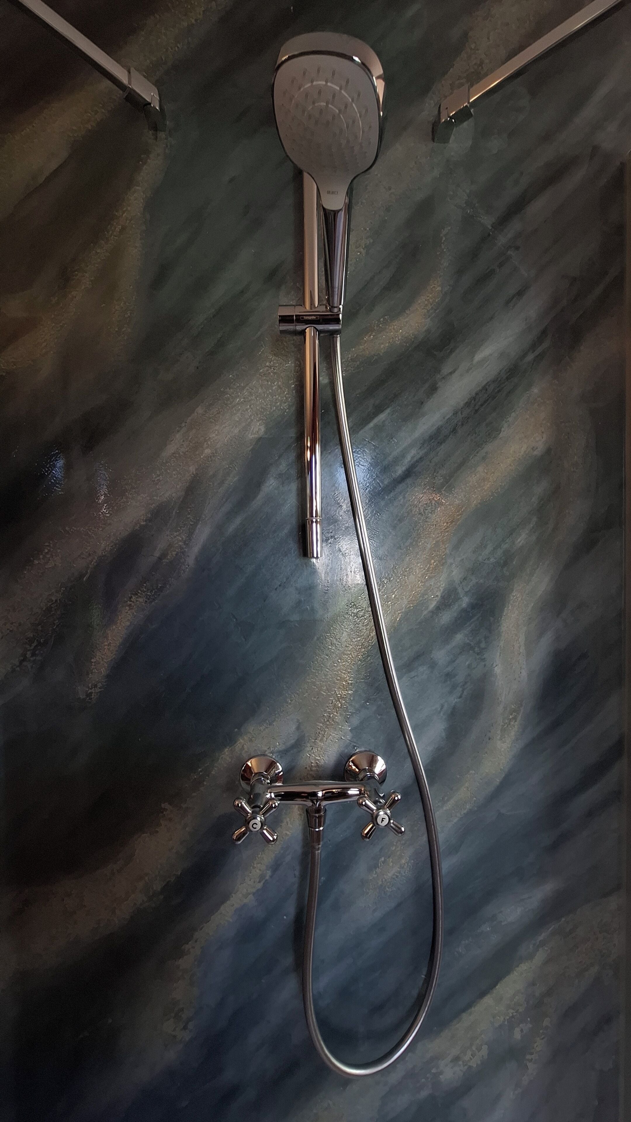Eine Duschbrause mit Handbrause, an einer Wand mit strukturierter Oberfläche angebracht.
