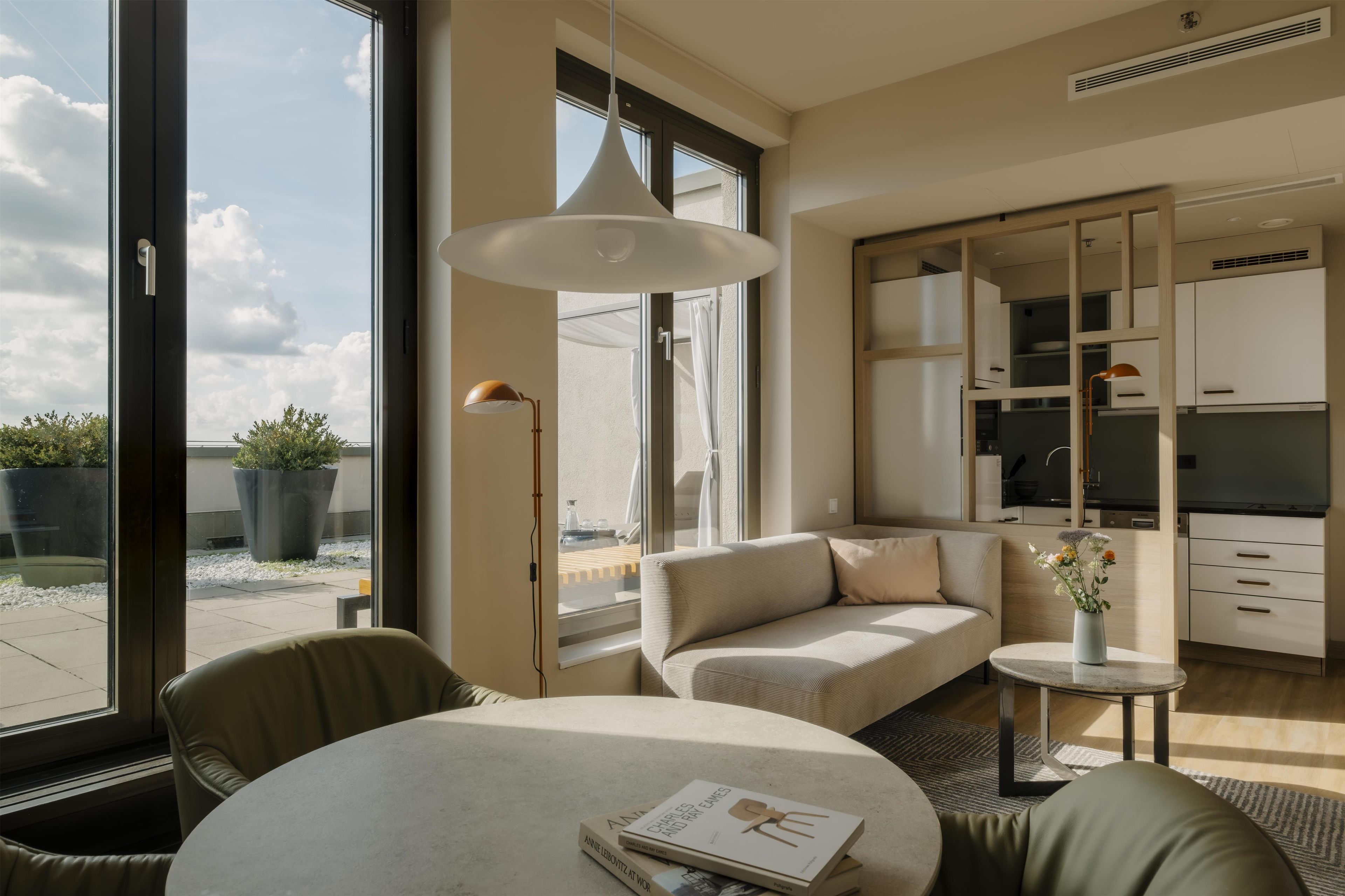 Un salon moderne avec un canapé, une table ronde et une suspension.