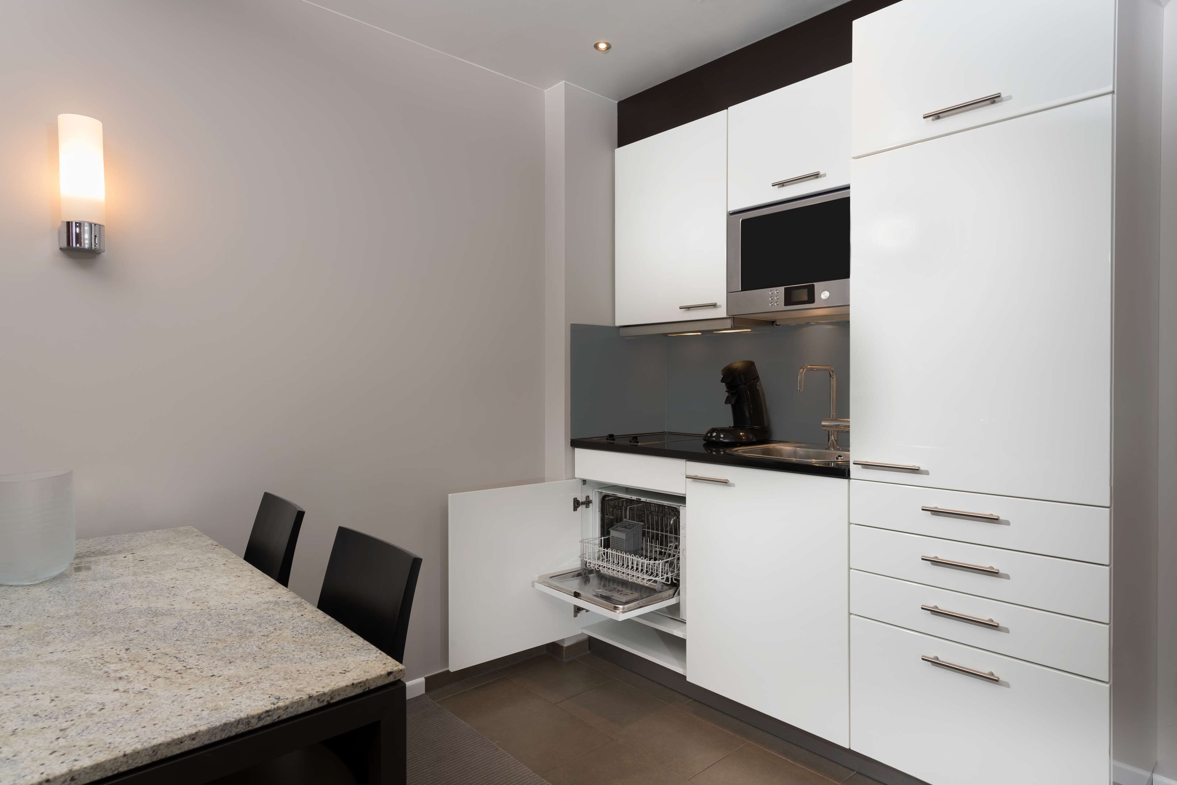 A modern kitchen with white cabinets, a black countertop, and a built-in oven.