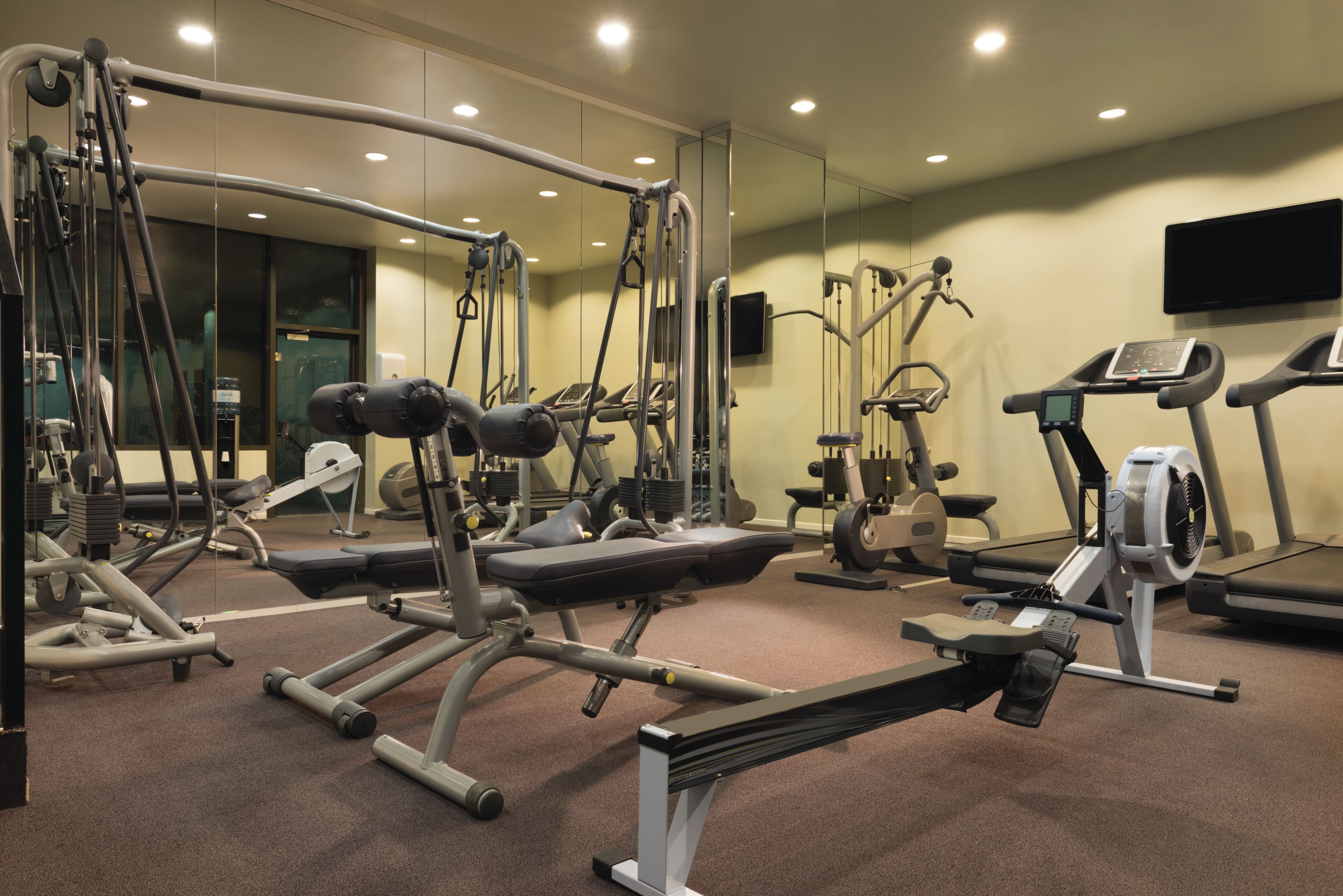 A gym with various exercise equipment including treadmills, weight machines, and a rowing machine.