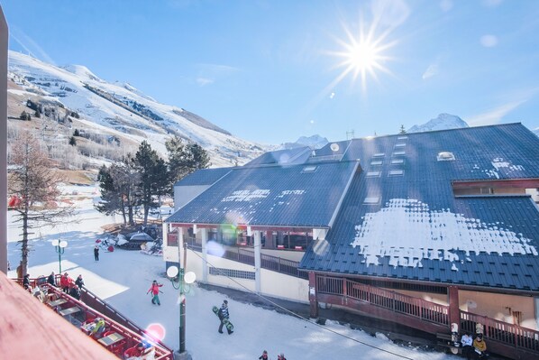 Estación de esquí con un edificio de techo inclinado y una montaña nevada al fondo.