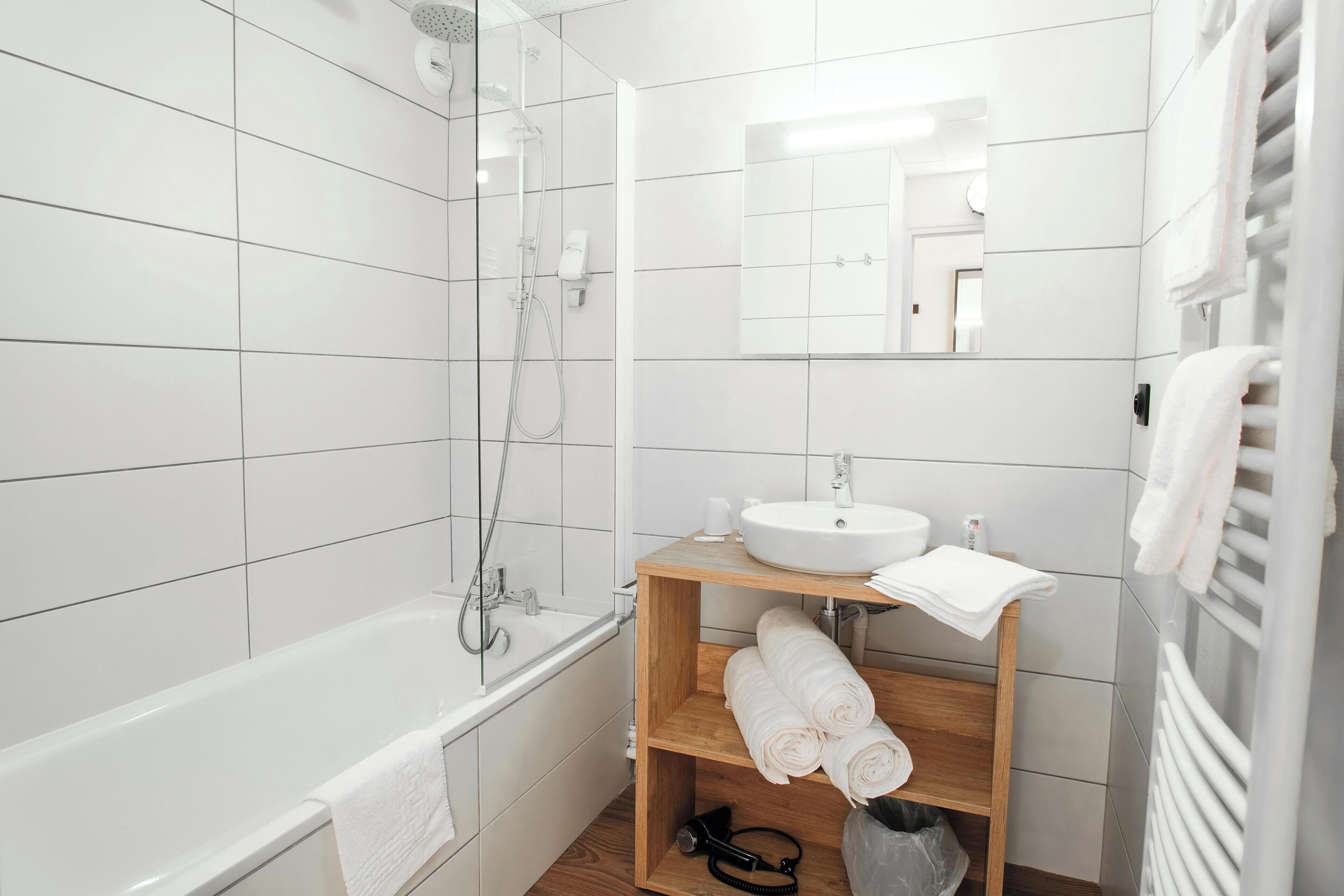 A modern bathroom with a bathtub, shower, and a vanity with a sink and mirror.