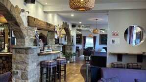 A cozy bar area with stone walls, wooden stools, and a hanging light fixture. - Twin Oaks Hotel (Chesterfield)