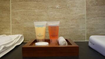 A wooden tray with two toiletries, a towel, and a white object on a counter.