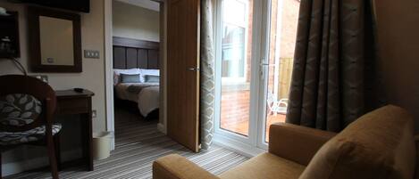 A hotel room with a bed, a desk, a chair, and a view of the outside.