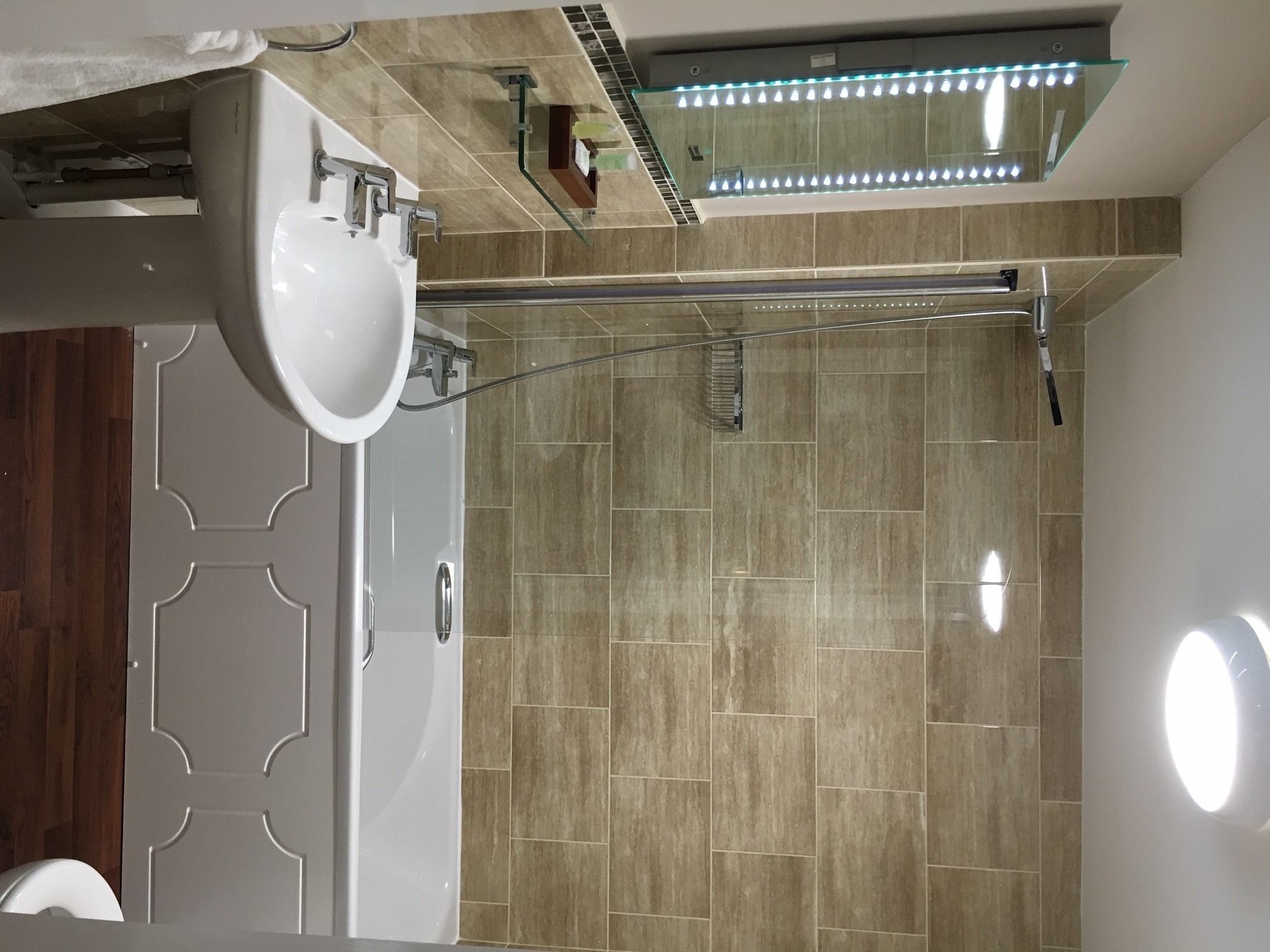 Een moderne badkamer met een douche, een wastafel en een spiegel.