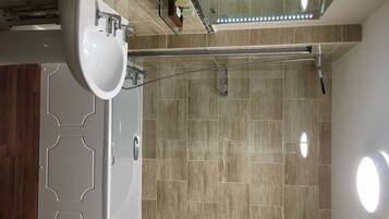 Een moderne badkamer met een douche, een wastafel en een spiegel.