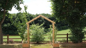 A wooden arbor structure in a garden setting with a wooden fence in the background. - Twin Oaks Hotel (Chesterfield)