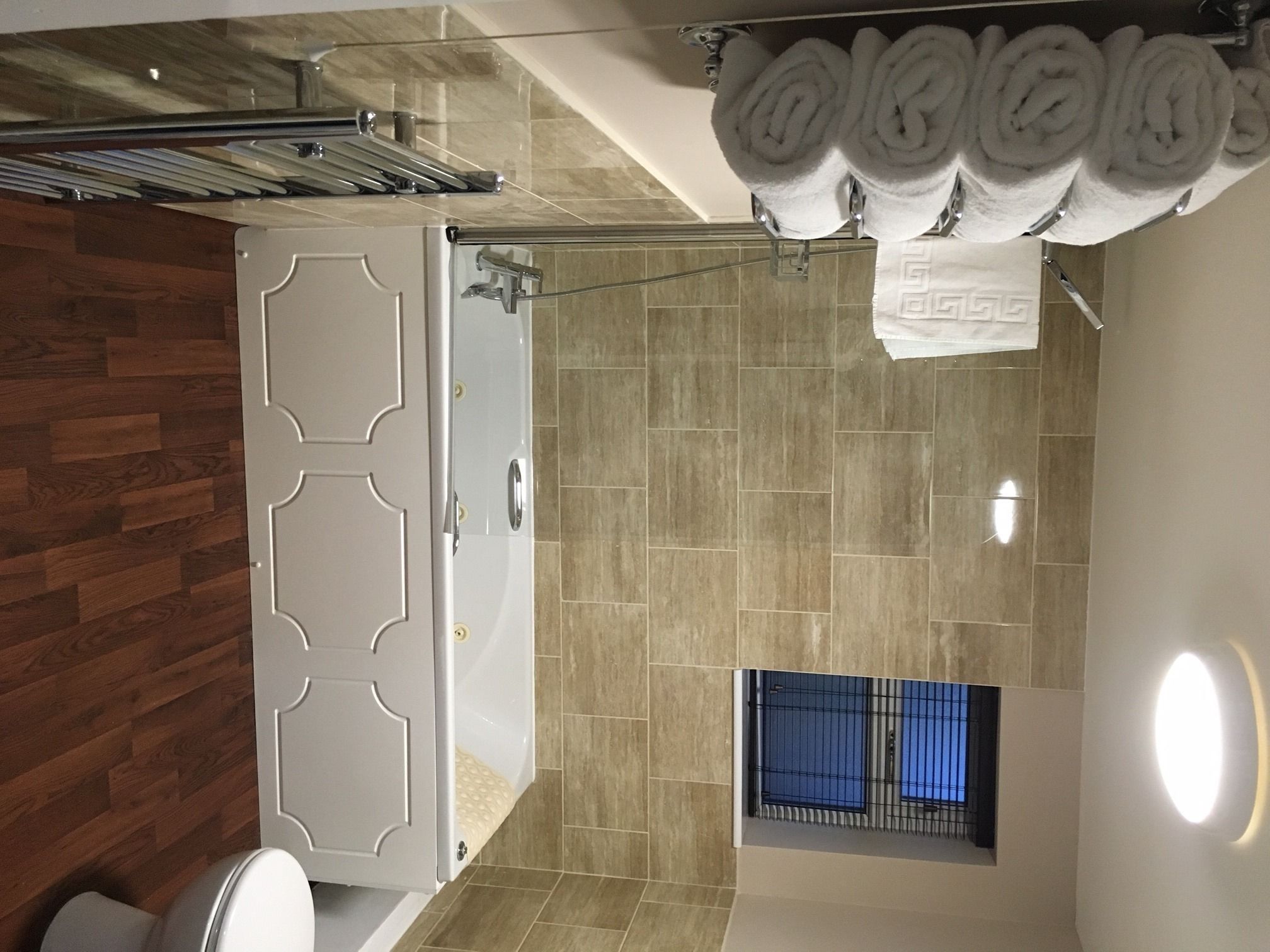 A modern bathroom with a shower, a toilet, and a towel rack.